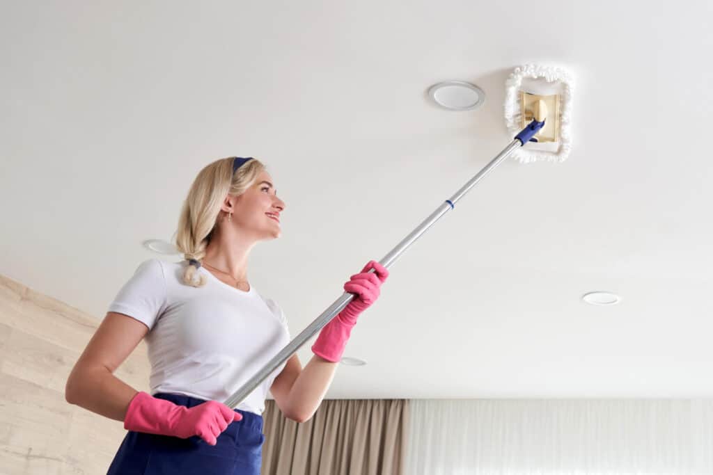 Femme nettoyant facilement un plafond avec balai télescopique microfibre sans échelle