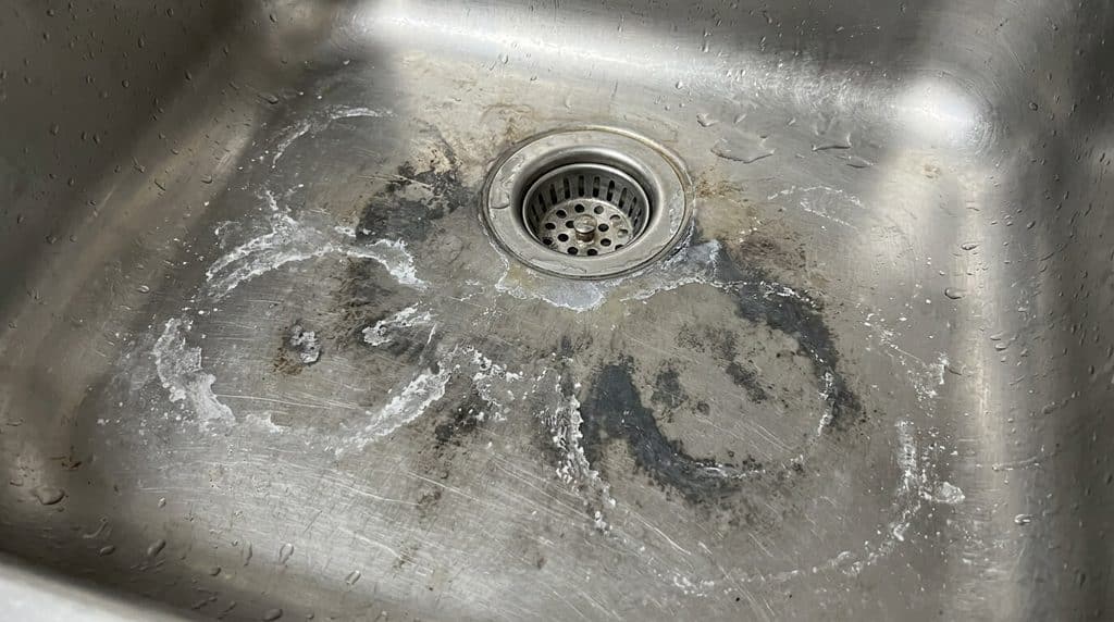 Évier inox taché par un acide : comment réagir 3 Traces blanches et auréoles grises de brûlure d'acide sur le fond d'un évier en inox.