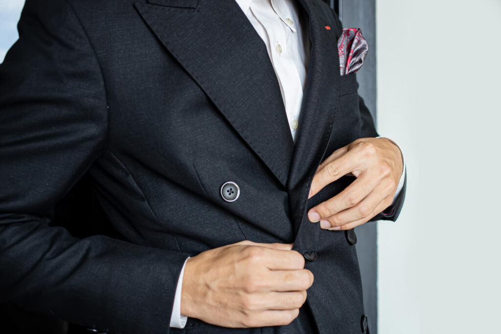 Main en train de découdre délicatement la poche cousue d'un manteau neuf.