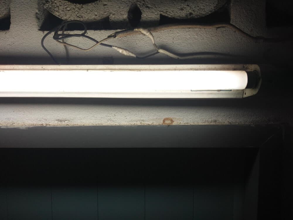 Un tube "néon" fluorescent qui clignote dans un garage, signe d'une panne.