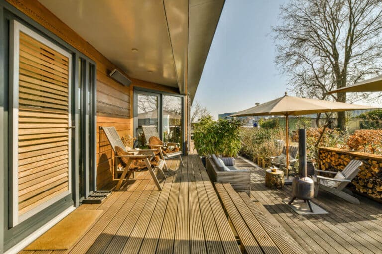 Terrasse en bois moderne sur deux niveaux, avec un espace repas en haut et un salon de jardin en contrebas.