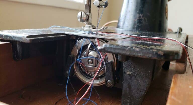 Amas de fils emmêlés bloquant le boîtier de la canette sous la plaque aiguille d'une machine à coudre