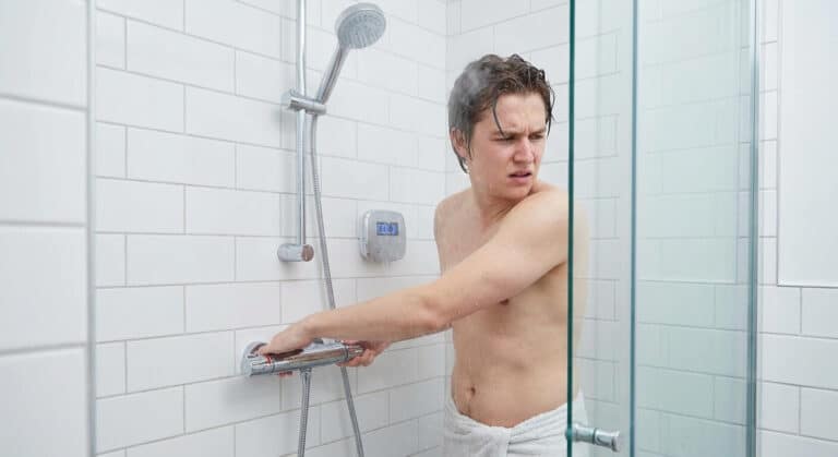 Utilisateur tournant la poignée de réglage de température d'un mitigeur thermostatique de douche sans obtenir d'eau chaude