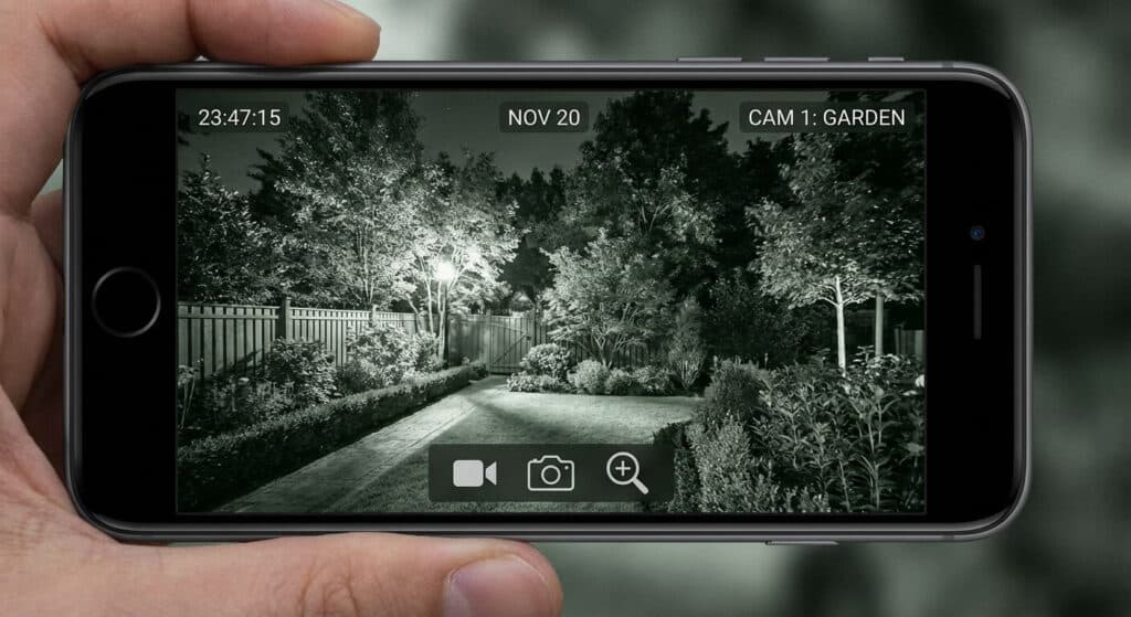 Capture d'écran d'un smartphone affichant la vision nocturne claire d'un jardin sécurisé par une caméra extérieure.
