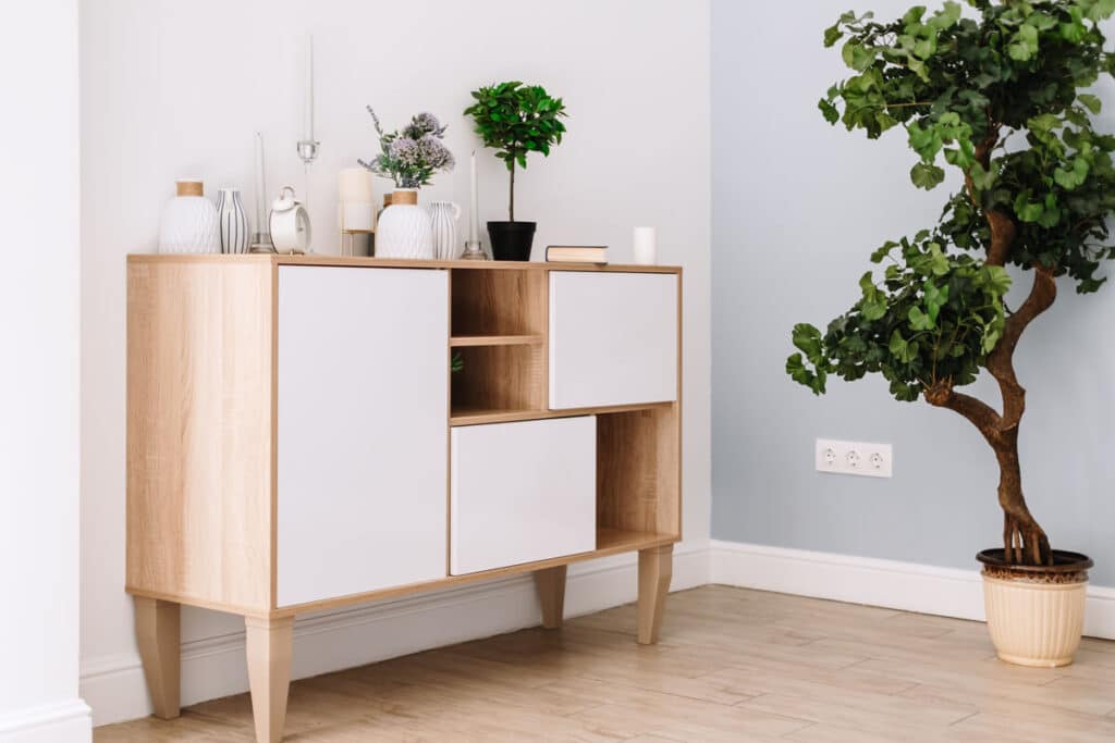 Un buffet haut contemporain servant de support décoratif avec des plantes et des cadres dans un séjour.