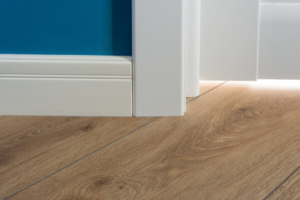 Détail de la découpe précise du parquet sous un chambranle de porte.