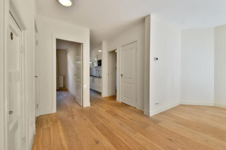 Accueil 1 Vue d'un parquet en chêne filant d'un couloir vers une chambre sans aucune interruption.
