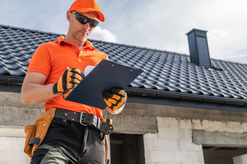 Travaux de toiture : pourquoi un seul devis ne suffit jamais 3 Un couvreur professionnel inspectant les tuiles et l'état de la toiture avant de rédiger un devis.