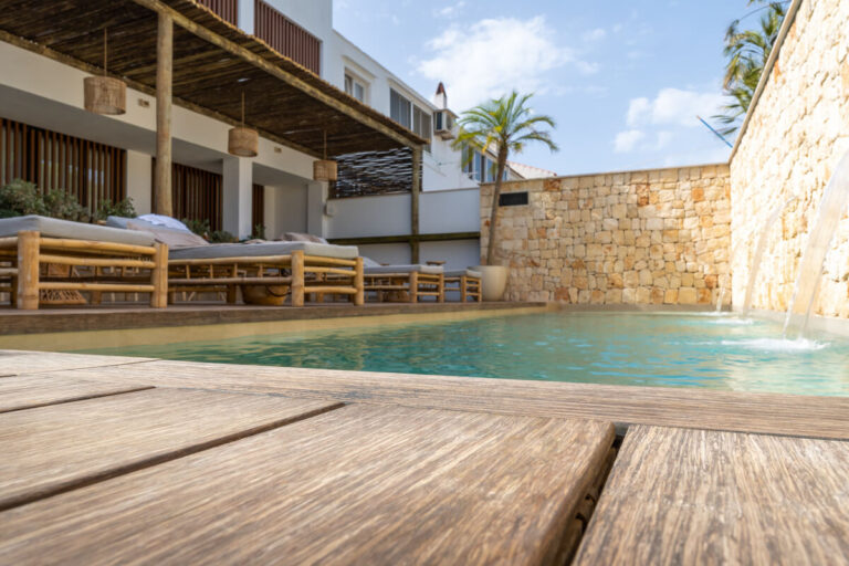 Une terrasse extérieure en lames de bois exotique entourant une piscine rectangulaire moderne.