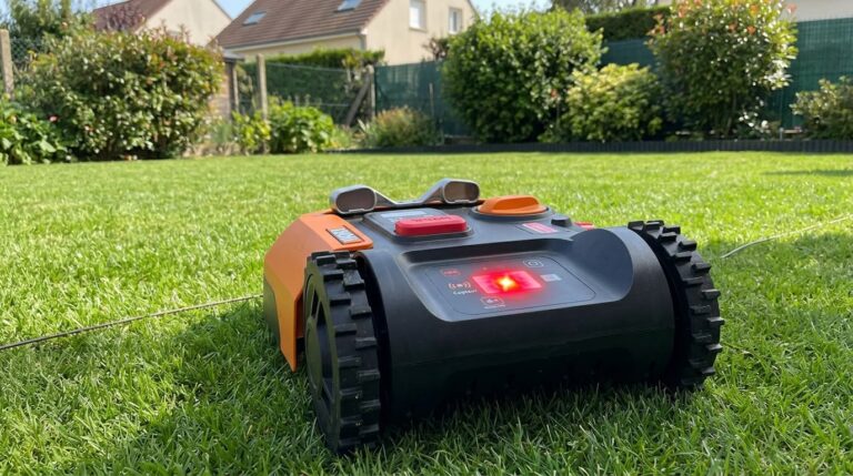 Un robot tondeuse Worx Landroid arrêté sur la pelouse avec un voyant d'erreur de capteur allumé.