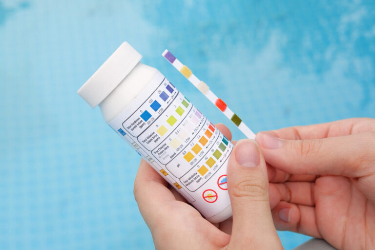 Un propriétaire de piscine analysant l'eau de son bassin à l'aide d'un kit de test colorimétrique.