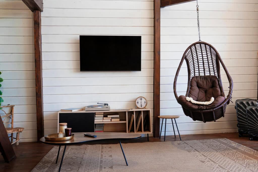 Un salon contemporain lumineux où le meuble TV en bois s'intègre harmonieusement au milieu d'étagères décorées.