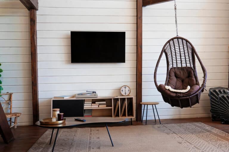 Un salon contemporain lumineux où le meuble TV en bois s'intègre harmonieusement au milieu d'étagères décorées.