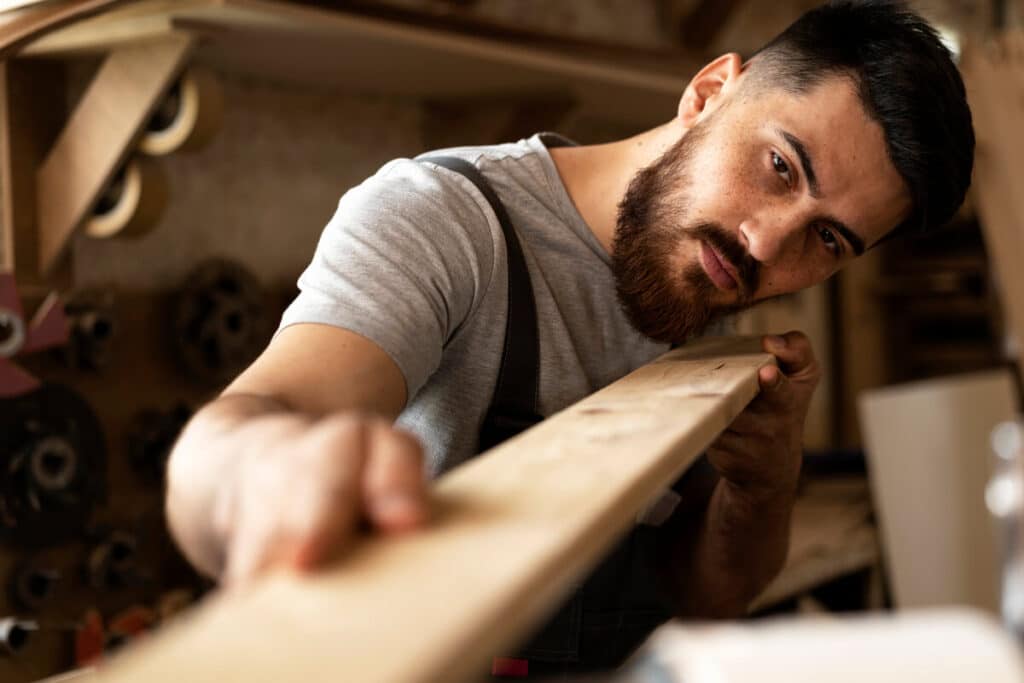 Un menuisier ébéniste en train d'ajuster une planche de bois dans son atelier.