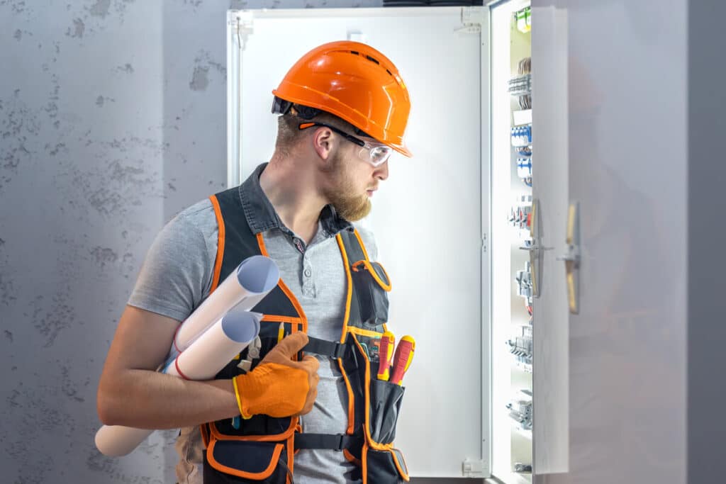 Un électricien professionnel procédant à la mise aux normes et au câblage du tableau électrique d'un logement ancien.