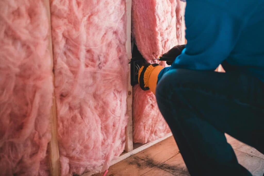 Entreprise d'isolation : comment choisir le bon professionnel pour ses travaux ? 2 Un professionnel certifié installant des panneaux d'isolation thermique sur les murs intérieurs d'une maison.