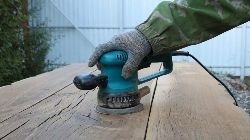 Ponçage de finition sur une poutre en bois mise à nu après l'élimination des couches de protection.