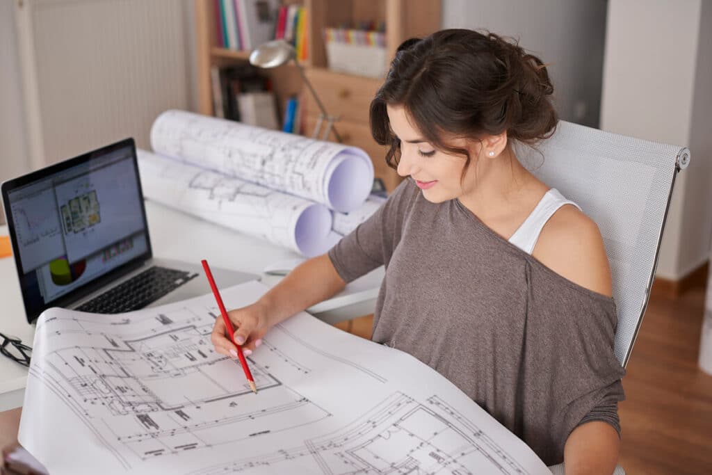 Un architecte d'intérieur dessinant des plans d'aménagement 3D sur sa table de travail.