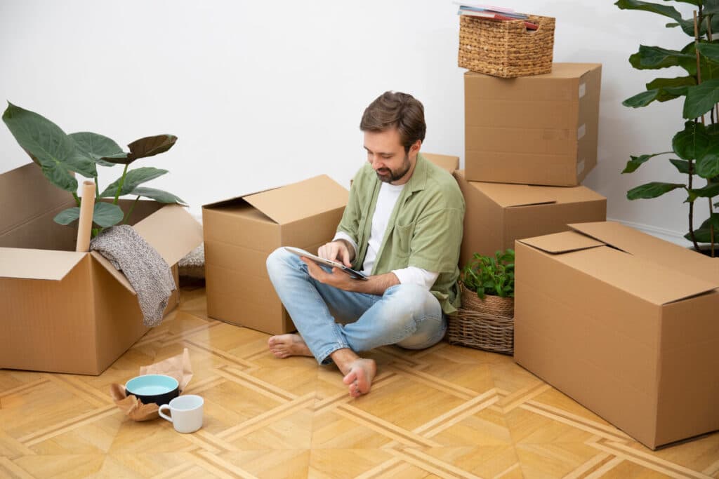 5 erreurs à éviter quand on débarrasse seul une maison encombrée 2 Une personne triant des cartons de déménagement et des objets dans une pièce encombrée.