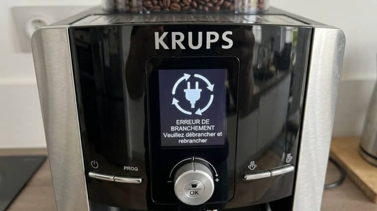 L'écran d'une machine à café Krups affichant le logo d'une prise électrique entourée de deux flèches.