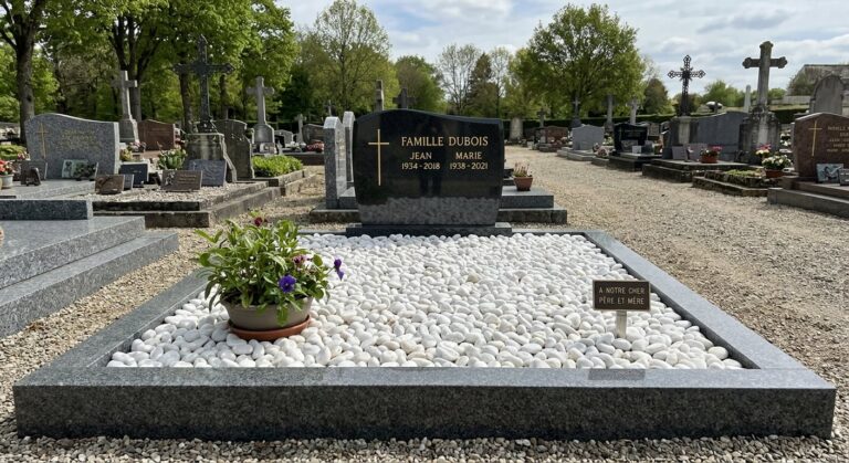 Entourage de sépulture réalisé avec bordures en granit et galets blancs décoratifs.