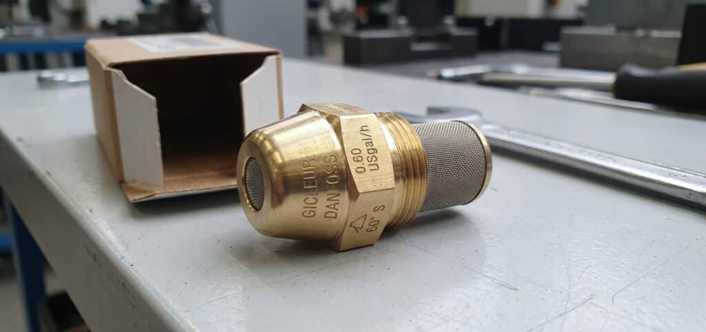 Gicleur de brûleur fioul neuf en laiton avec marquage de débit et d'angle.