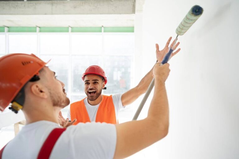Artisan appliquant une sous-couche de peinture sur un mur avant la pose du carrelage.