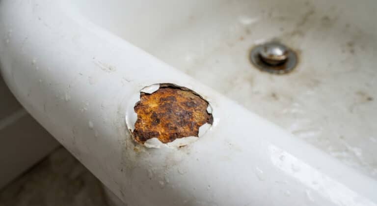 Accueil 1 Éclat d'émail au fond d'une baignoire en fonte laissant apparaître une plaque de rouille orangée.
