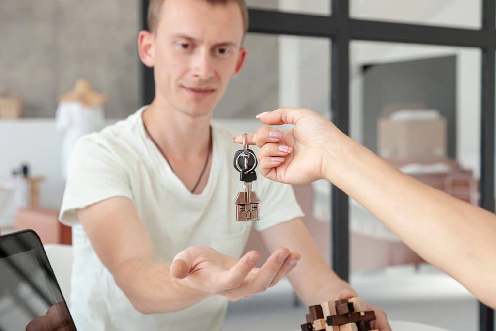 Constructeur remettant les clés d'une maison neuve terminée à un couple de propriétaires.