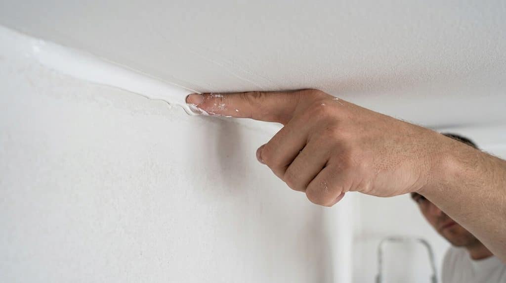 Joint acrylique lissé au doigt le long de la jonction mur plafond avant peinture.