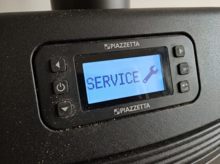Accueil 1 Écran de commande digital d'un poêle à granulés Piazzetta affichant le message Service avec une clé.